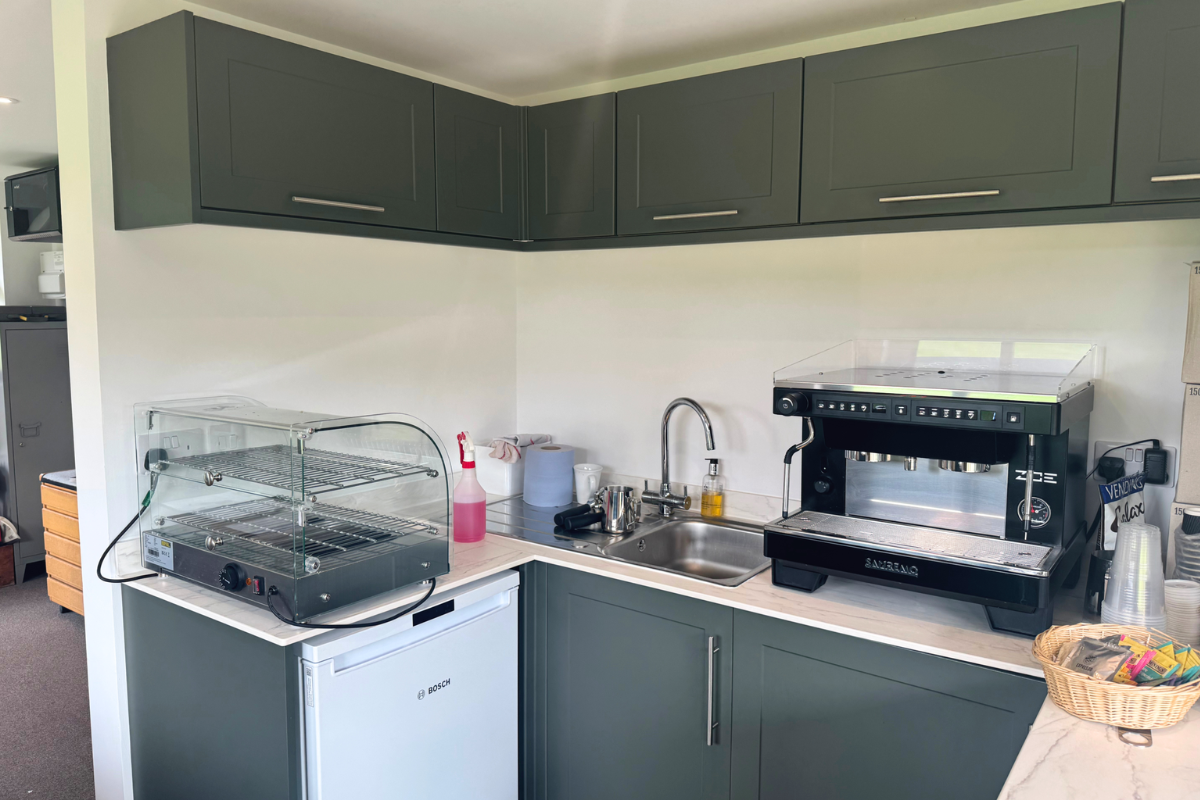 Kitchen cabinets in golf hut with fridge, sink and coffee machine